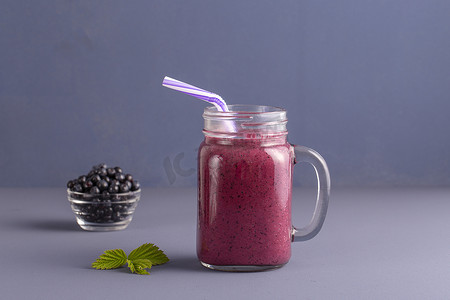 蓝莓果汁摄影照片_健康饮食, 饮食, 节食和素食概念-从蓝莓和香蕉在玻璃杯, 关闭冰沙。新鲜蓝莓和果汁在灰色背景下