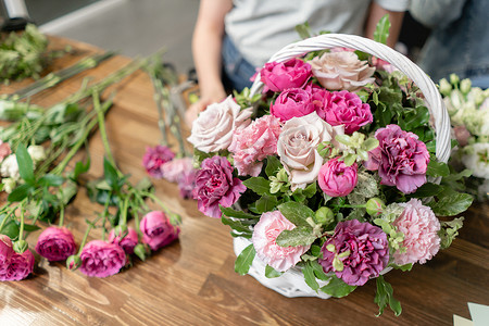 女花匠在柳条篮中制作花。美丽的混合花束。花卉店概念。漂亮的新鲜花束。鲜花递送
