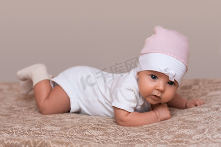 可爱的新生女孩在床上爬行, 穿着漂亮的粉红色帽子, 傻傻地看着镜头。小宝宝 ejoys 时间与父母在一起。小可爱的女儿在卧室里。童年和秀丽概念