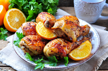 oil摄影照片_Baked chicken drumstick with orange, smoked paprika, Provencal herbs and olive oil.