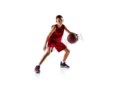 红色的篮球摄影照片_全长的男孩肖像，身穿红色制服训练的篮球运动员被隔离在白色背景之外。流口水