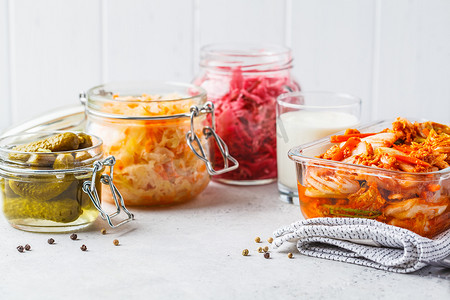 泡菜摄影照片_益生菌食品概念。泡菜、甜菜泡菜、泡菜、凯菲尔和腌制黄瓜在玻璃瓶, 白色背景.