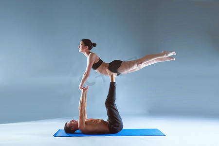 双人瑜伽摄影照片_年轻夫妇一起练习杂技瑜伽工作室在垫子上。杂技。几个瑜伽。双人瑜伽.