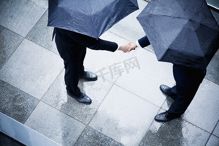 雨中撑伞摄影照片_商人在雨中握手