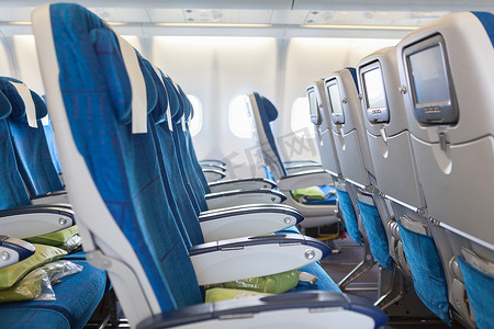 座椅摄影照片_空舒适的座椅中的巨大飞机客舱与屏幕在椅子背