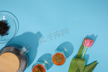 郁金香花摄影照片_茶杯、茶壶和美丽的郁金香花在蓝色的顶部视图