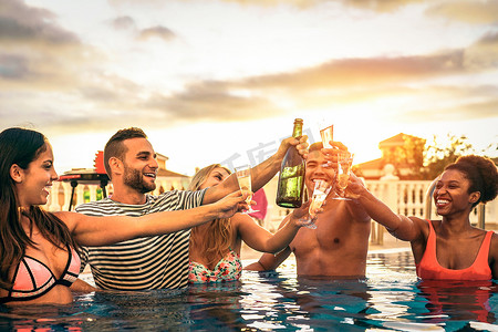 一群快乐的朋友, 让一个游泳池派对欢呼与香槟在日落-年轻人笑着和乐趣与波光粼粼的葡萄酒在奢华的热带度假胜地-青年生活方式概念的烘烤