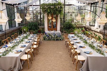 宴会厅摄影照片_婚礼宴会厅在温室里，桌上摆满了鲜花、蜡烛、水晶吊灯。软性选择性重点.