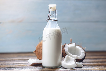 椰子奶在一个瓶子与白色肉在蓝色木背景。美容中使用的有机健康产品