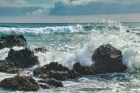 海浪汹涌摄影照片_汹涌的海浪冲击着海岸的岩石