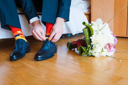皮鞋主图摄影照片_那个红色的皮鞋袜子站在木地板上接下来到一束白色和黄色鲜花与绿