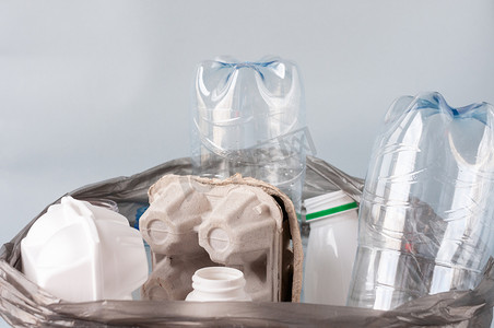 玻璃瓶子摄影照片_塑料，分类的垃圾放在一个轻便的背景的袋子里，白色的瓶子，纸，玻璃。生态概念、垃圾分类 .