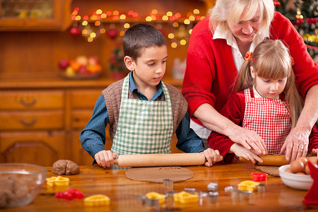 祖母和小女孩和男孩烘烤圣诞蛋糕在 th
