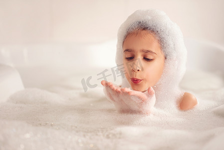 泡泡摄影照片_这个女孩在浴室里洗澡和玩耍泡沫。这是一个很大的下降。吹泡泡