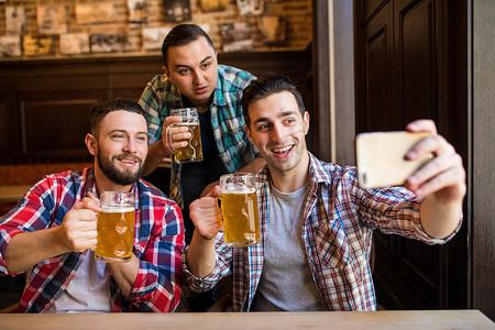 快乐的男性朋友拍照并喝啤酒在酒吧或酒馆