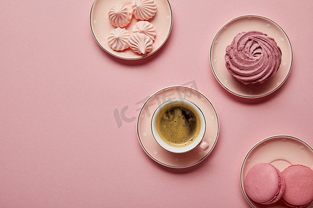 飞碟背景摄影照片_粉红色点缀飞碟的顶视图，粉红色背景有梅林格、马卡龙和一杯咖啡
