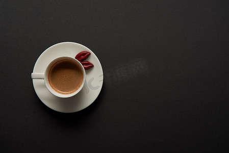 杯咖啡的顶部视图与巧克力嘴唇在飞碟在黑色背景