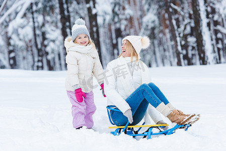 一起看看表情包摄影照片_愉快的女儿和母亲雪橇一起在冬天公园