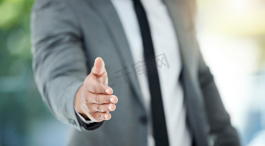 an unrecognizable businessman reaching out for a handshake while standing in his office.