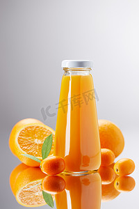 橙汁和金橘在反光面上的瓶