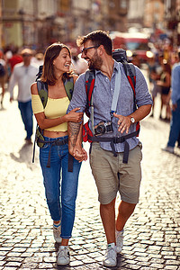 在美丽的天气里，一对年轻貌美的旅游夫妇在城市街道上谈恋爱