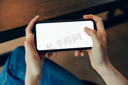 social摄影照片_Closeup of young woman hand holding smartphone on the table and the screen is blank, social network concept.	