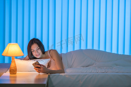 The cute woman lay on the bed and phone. Evening night time
