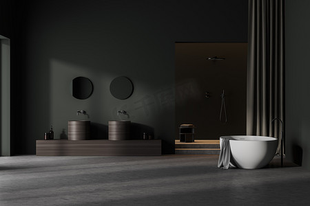 grey摄影照片_Dark grey bathroom interior with wooden sinks and round mirrors, front view. White bathtub and shower on background, concrete grey floor, 3D rendering