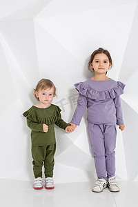 在相同服饰的不同颜色，在工作室里的白色背景上的小女孩两姐妹 1.5 和 5 岁儿童