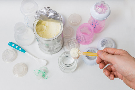 奶粉罐光圈摄影照片_手努力做好毕业生为从瓶子里喂养的婴儿配方奶粉.