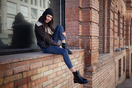 Outdoor lifestyle portrait of pretty young girl, wearing hipster swag grunge style on urban background. Wearing hat and jeans with backpack. Spring fashion woman. Toned style instagram filters.