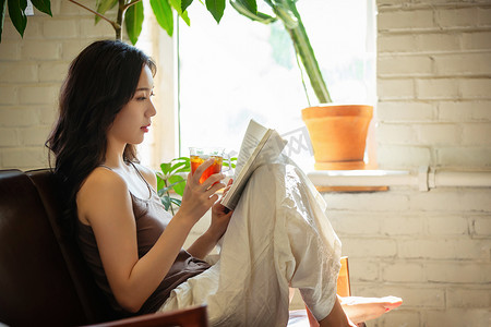 热茶摄影摄影照片_年轻女人在家喝茶看书