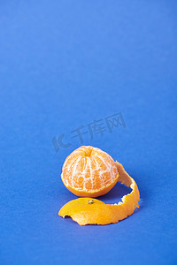在蓝色背景上带着热情去皮多汁的橘子 