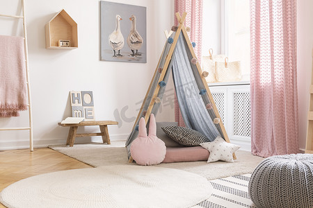 粉红色海报摄影照片_在女孩的卧室内部的帐篷前的粉边枕头与粉红色的窗帘和海报。真实照片