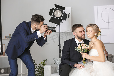 studio摄影照片_Photographer working with young wedding couple in studio