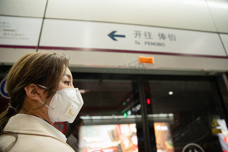 戴口罩的年轻女人站在地铁站台上