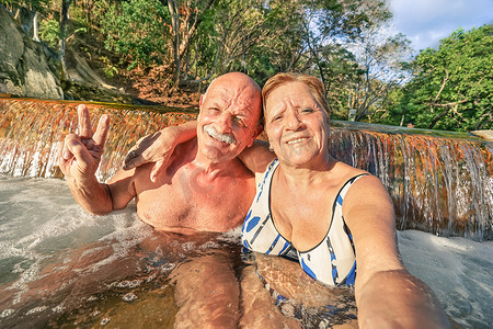 hot摄影照片_Senior happy couple taking selfie at Maquinit Hot Spring in Coron - Relax concept to Philippines wonders and active elderly traveling around the world - Warm afternoon color tones with tilted horizon