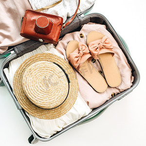 手提行李摄影照片_手提行李与夏季女性服装和复古相机在白色背景。平躺, 顶部视图。夏日时尚理念.