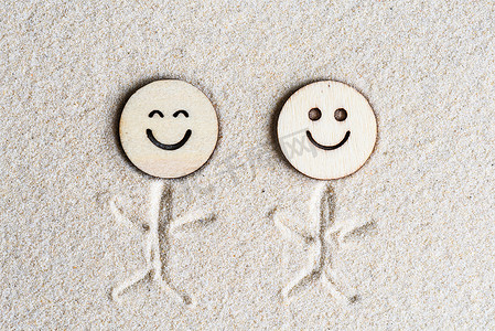 两个有趣的，快乐的木制笑脸在沙滩上。 概念。 平躺在床上 空中景观