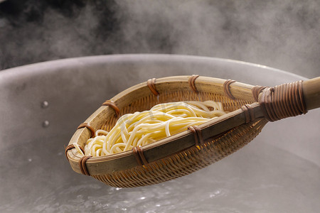 锅里的面条摄影照片_竹竿拿起锅里的热面条，面条牙有胃口