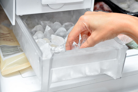 一个女人从冰柜里拿出冰块来冷却饮料