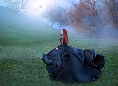 神秘的女孩与红色的头发运行从森林在华丽的蕾丝皇家礼服与飞光长火车，女士在绿色冰冻的草地和雾，女巫变成黑乌鸦和飞向太阳