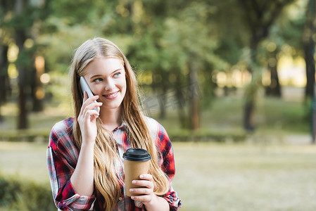 时事要闻摄影照片_・时事：美女在休闲装中挑纸咖啡杯 在智能手机上说话，看着远方