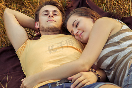 Loving couple lying down on floral field in autumnal park, warm sunny day, enjoying family, romantic date, happiness and love concept. relaxing and rest with closed eyes. sleep.