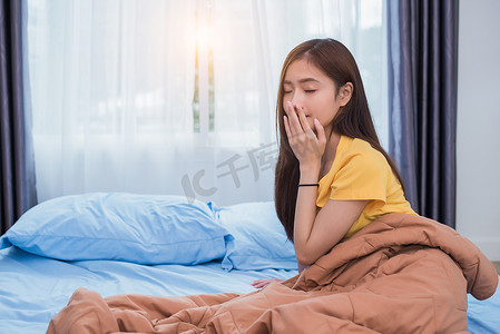 亚洲妇女早上起床在卧室懒惰的姿势 