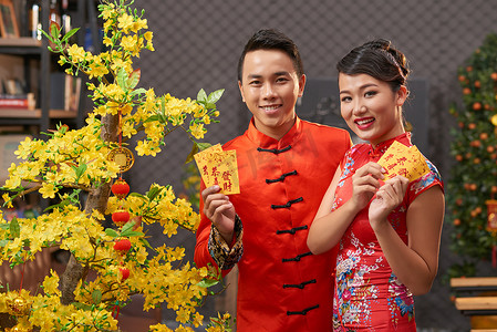 爱好亚洲情侣穿着中国传统服饰, 展示彩色信封 