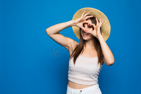 特写肖像微笑开朗快乐的年轻女子做心脏标志用手在顶头被隔绝的蓝色背景。积极的人的情感表达感觉生活知觉态度身体语言