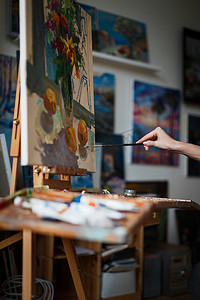 一个女人在画布上用画笔和颜料在她的艺术工作室里画画。框架只是女人的手.