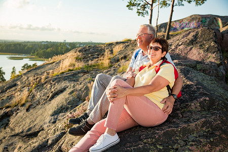 探索海洋摄影照片_爱的老夫妇徒步, 坐在岩石的顶端, 探索。活跃成熟的男人和女人拥抱和愉快的微笑。海湾和海洋的风景。健康的生活方式。芬兰.