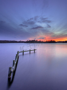泡七彩泡摄影照片_在平静的湖面的木结构建筑的紫色落日